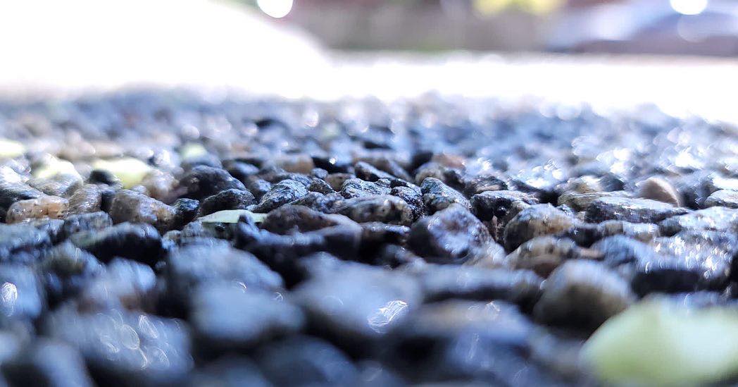 Close-up of wet textured pebbles or gravel surface with scattered light reflections.