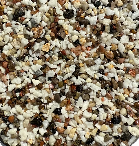 Close-up of mixed small stones and grainy particles in white, brown, black, and beige tones.